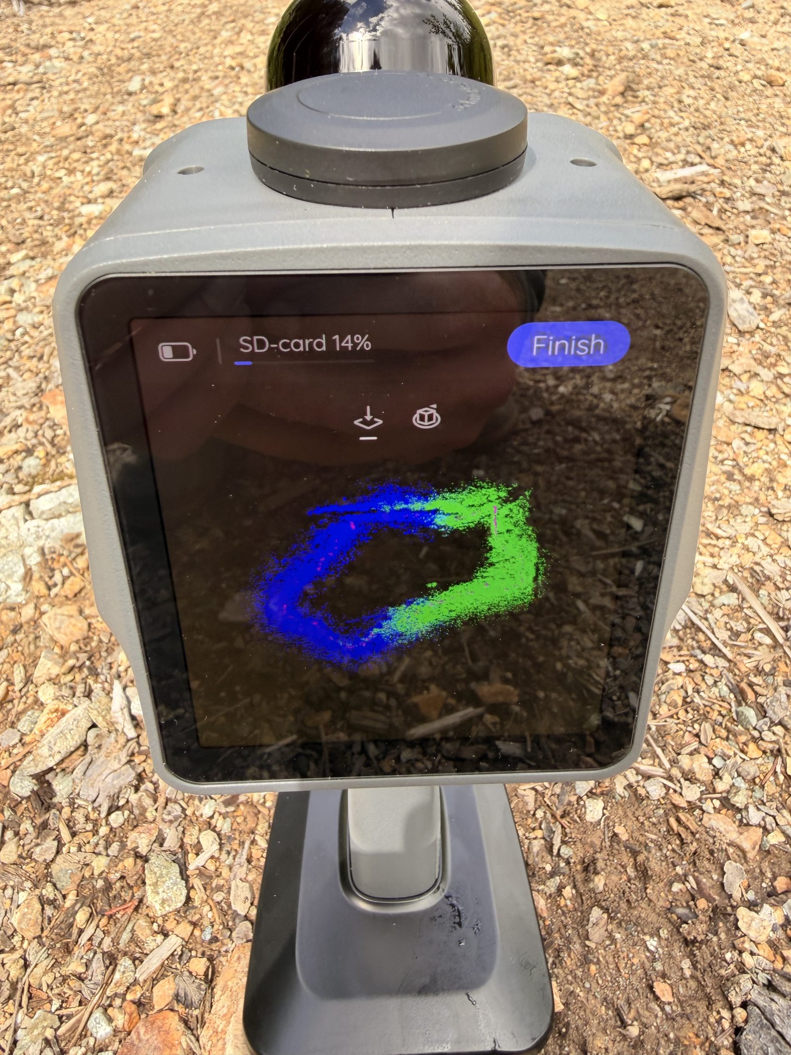 Handheld SLAM LiDAR unit on its pole, screen showing a scan loop in progress